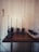 Four walkie-talkies are neatly placed on a wooden table, each positioned in its own charging dock. A power strip with multiple outlets is placed to the right, with cables connected to each device. The background consists of a light-colored wooden wall, creating a minimalist and organized setting.