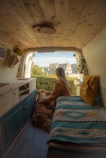 a woman sitting in the back of a van with a dog