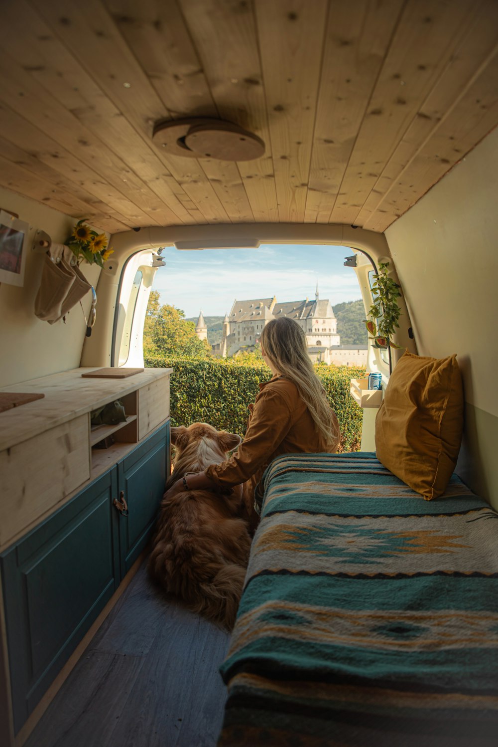 a woman sitting in the back of a van with a dog