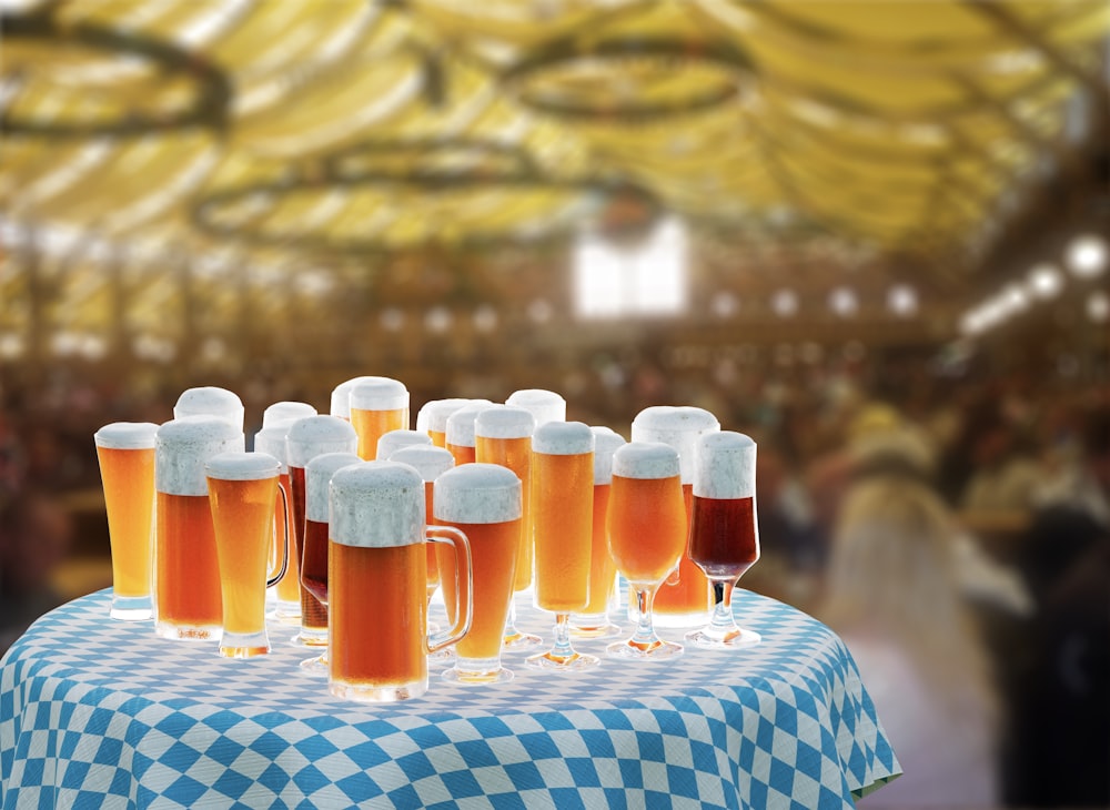 Una mesa cubierta con muchos vasos de cerveza