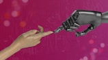 two hands touching each other in front of a pink background