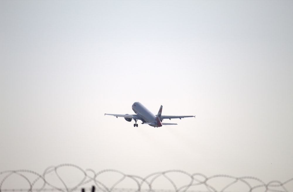 an airplane is flying over a barbed wire fence