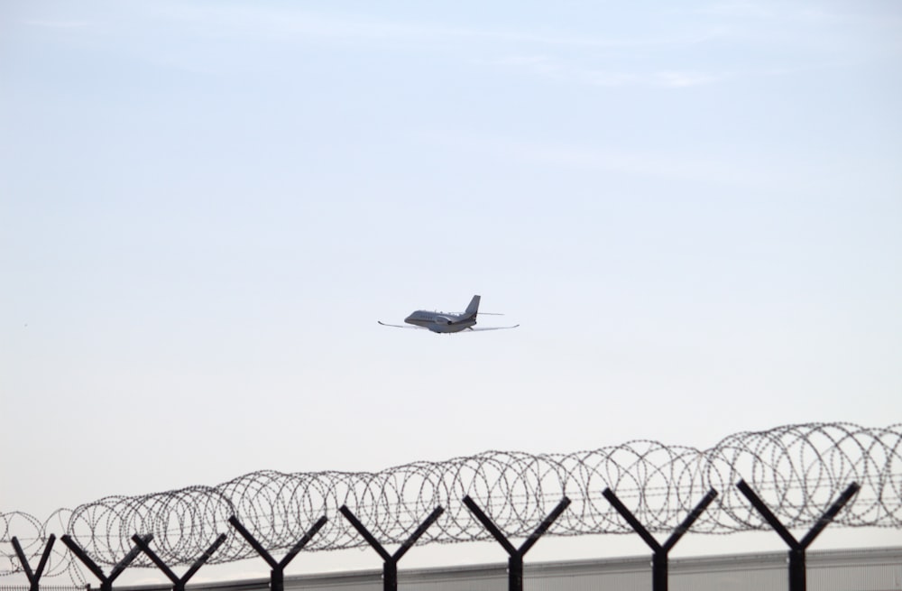 a plane flying over a barbed wire fence