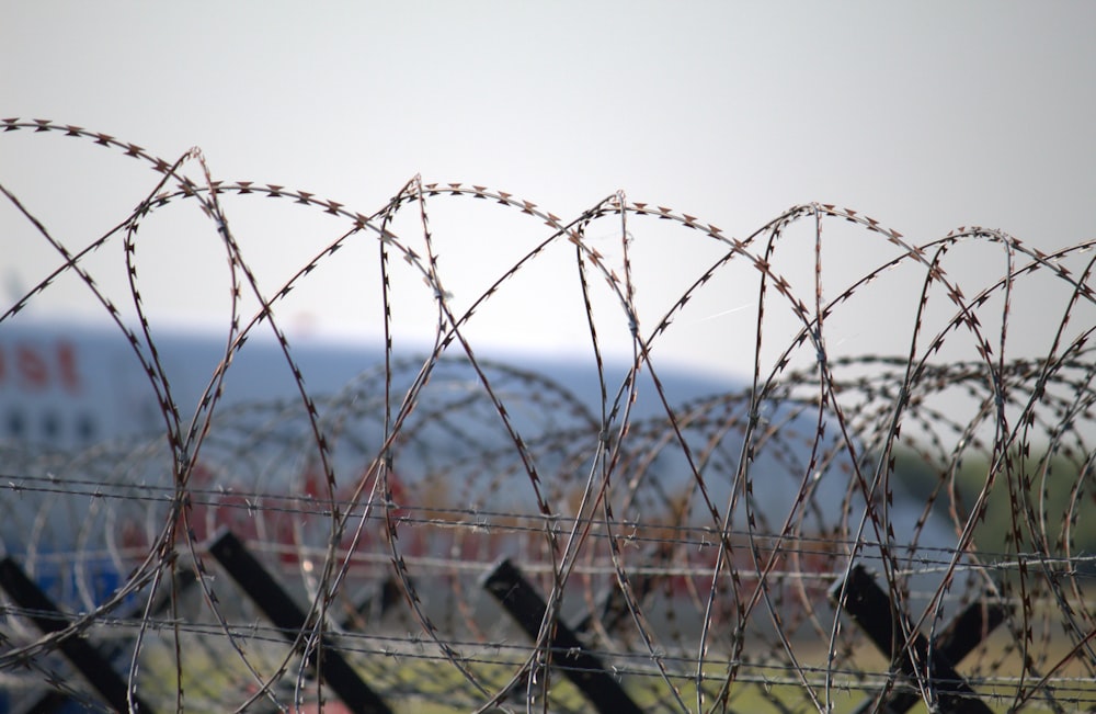 a barbed wire fence with a plane in the background