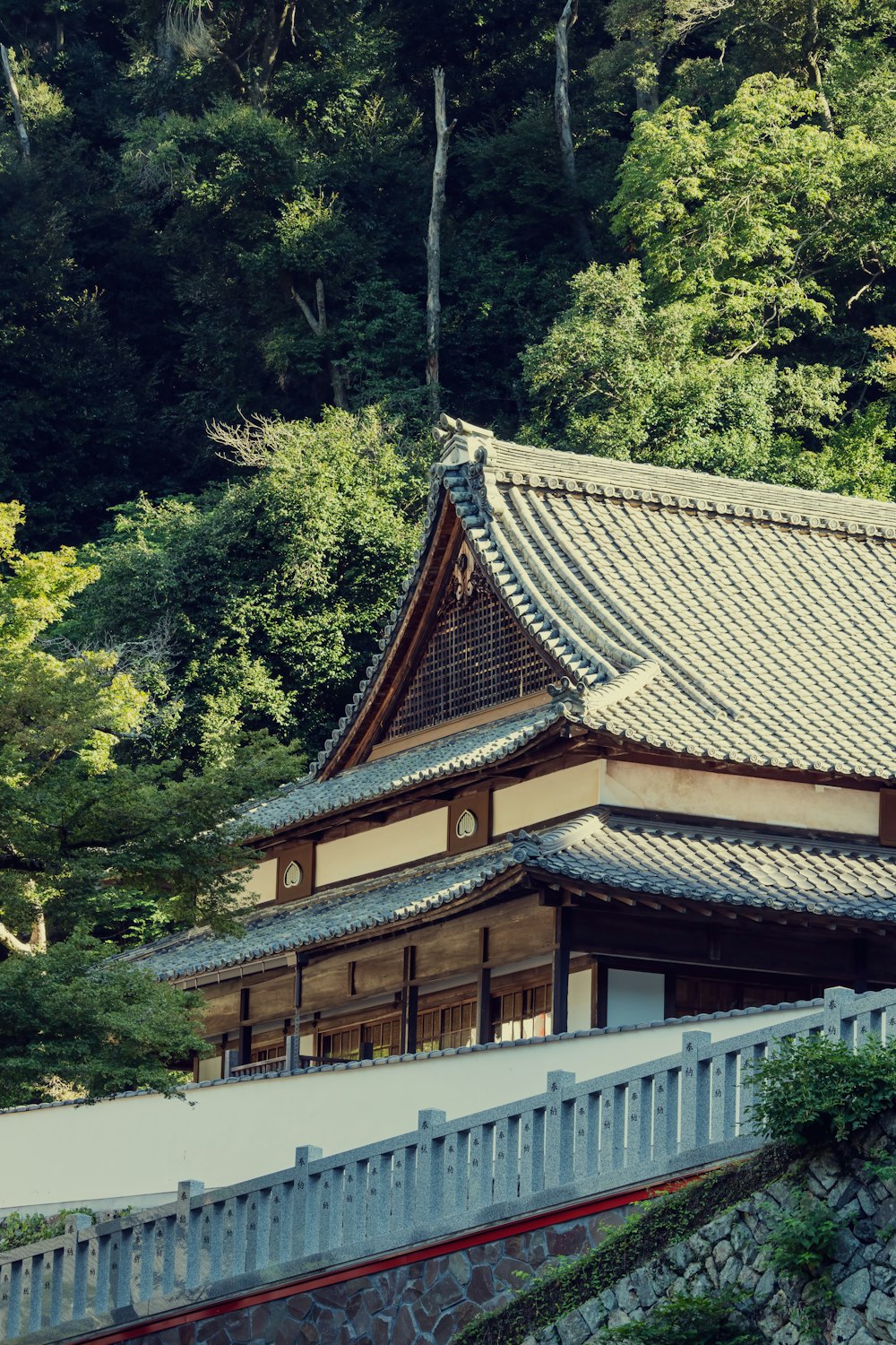 a tall building with a roof in front of a forest