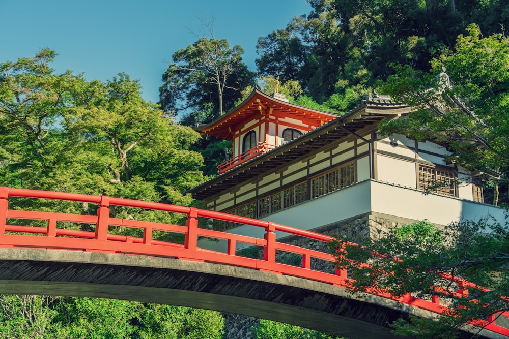 a red bridge crosses over a river in front of a building