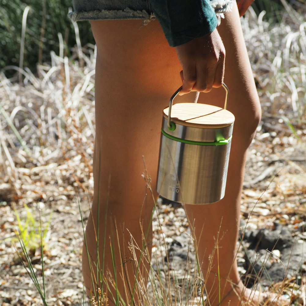 a person holding a metal bucket in a field