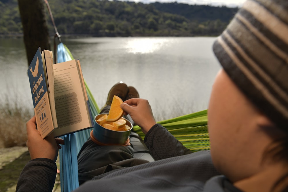 a man reading a book while sitting in a hammock