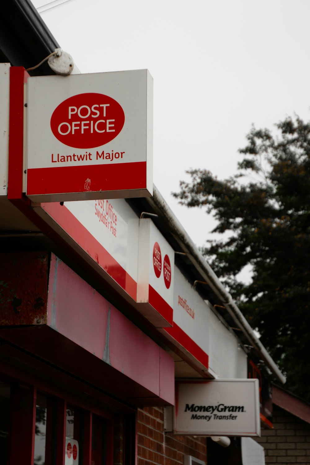 a post office sign hanging from the side of a building