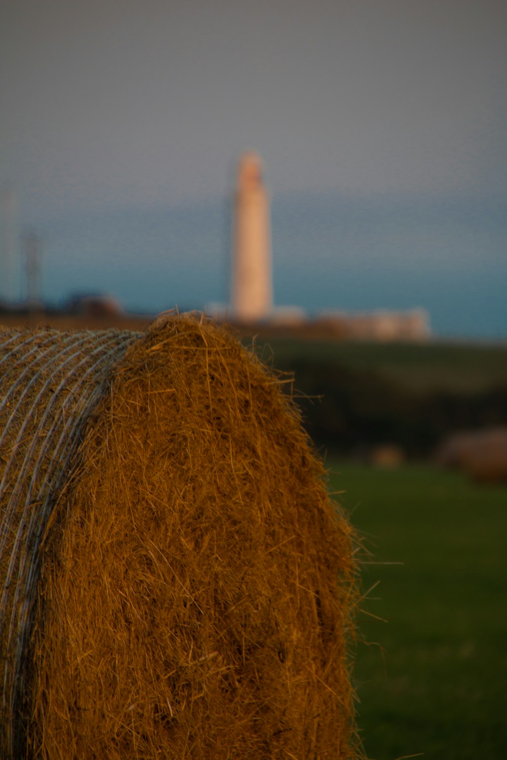 a bale of hay with a lighthouse in the background