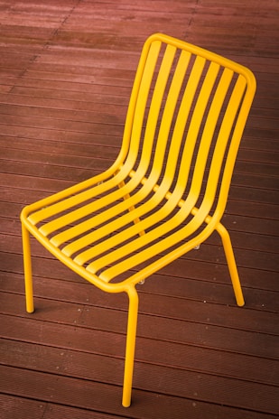 Close-up of a sleek aluminum lounge chair bathed in warm afternoon light on a wooden deck.