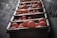 A row of plastic crates filled with ripe oranges arranged in an orderly fashion. The crates are lined up against a wall, creating a visually appealing pattern. The scene is lit in a way that highlights the vibrant color of the fruit, casting subtle shadows.