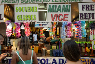 A lively fundraiser event with a crowd gathered around a Wheeze the Juice booth, bright signs promoting the cause, and refreshing drinks being served.
