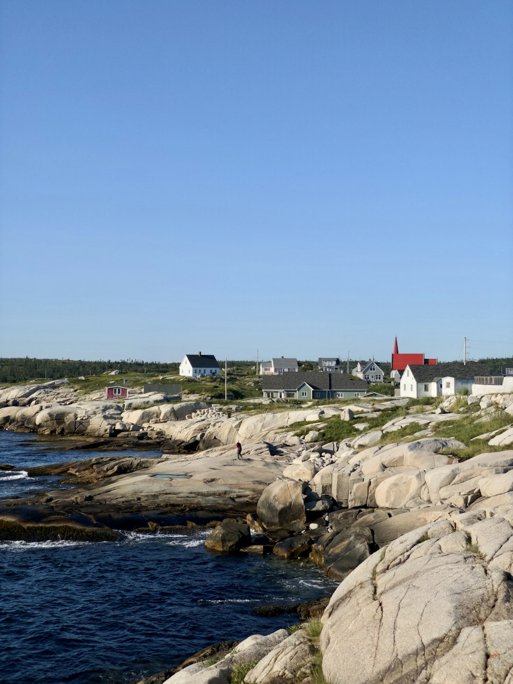 a lighthouse on a rocky shore with houses in the background