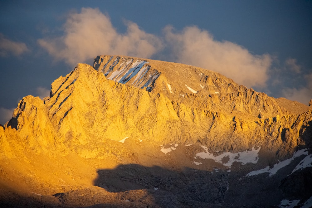 Una montagna molto alta coperta di neve sotto un cielo nuvoloso