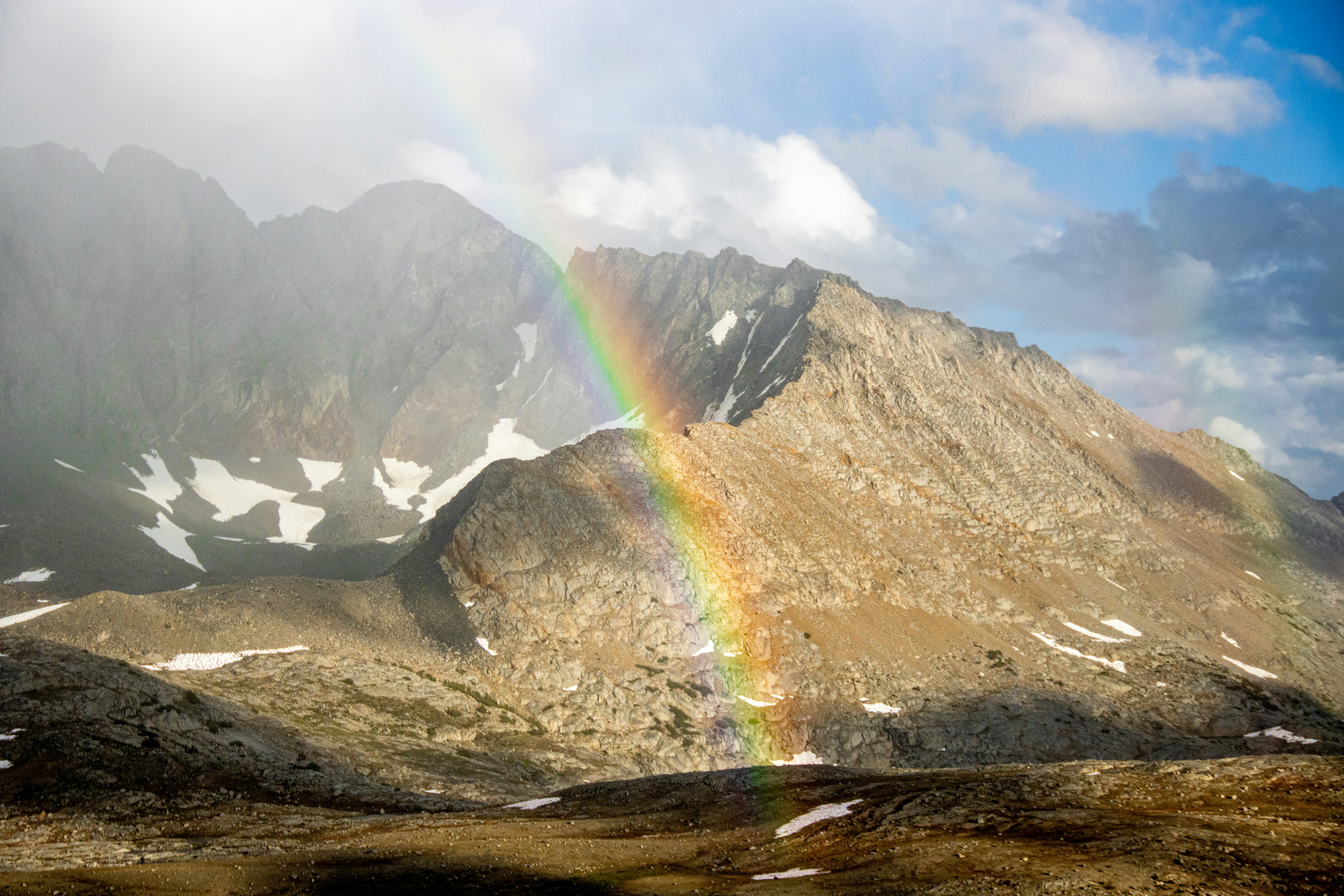 a rainbow in the sky over a mountain range