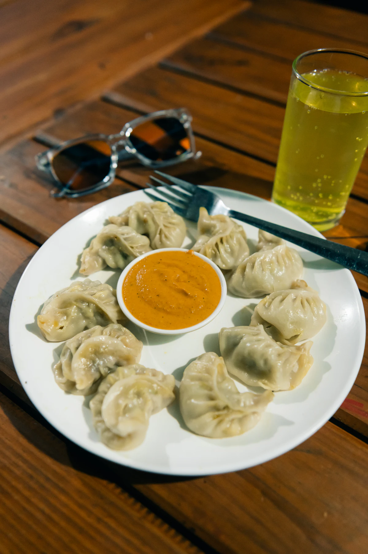 Steamed momos plated with a pot of tomato achar