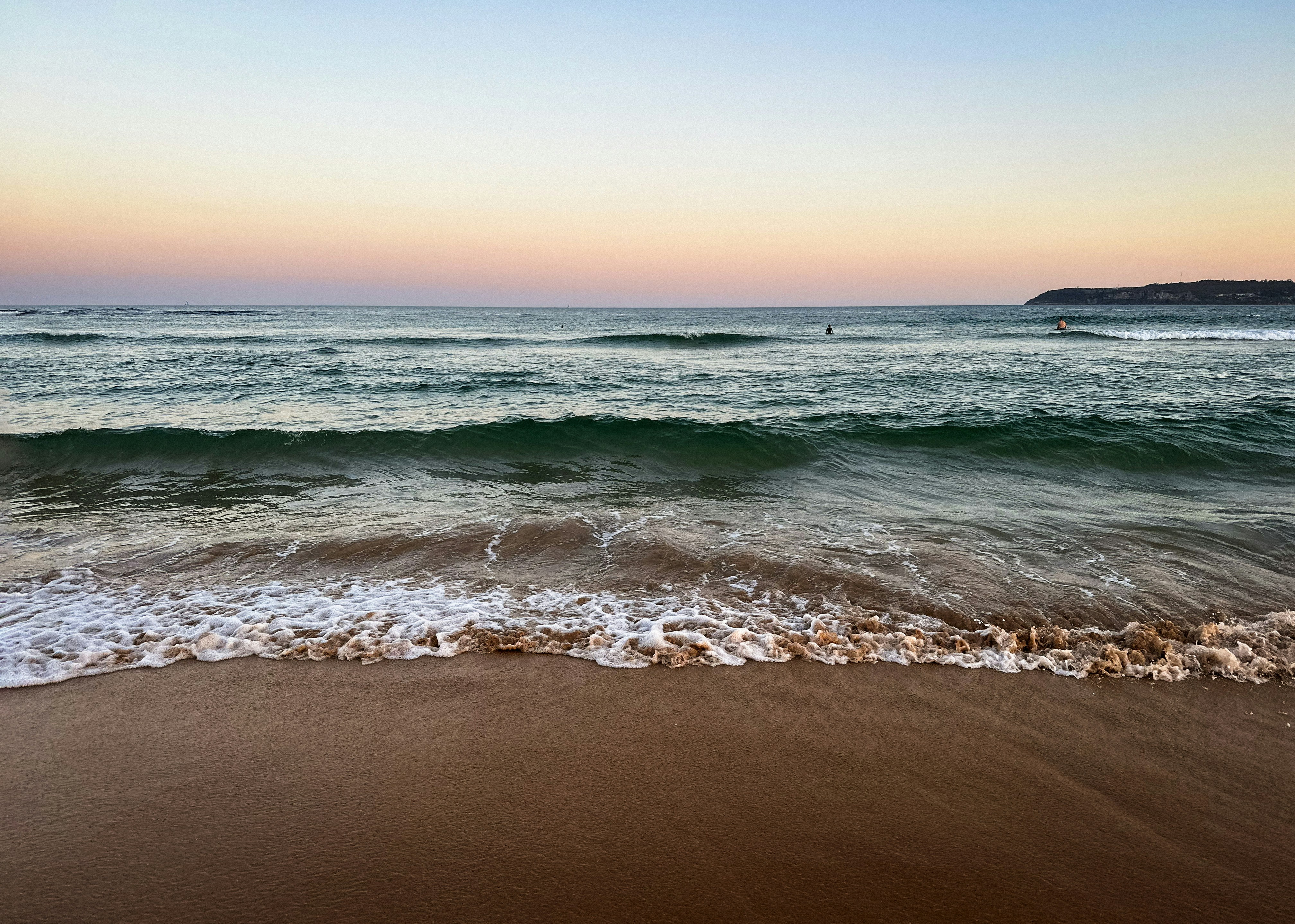 A sandy beach with waves coming in to shore photo – Free Beach Image on ...