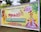 A colorful banner promoting an event called Grand Onaghosham, featuring traditional Kerala imagery including a Kathakali dancer and a mythological figure with an umbrella. The event is set for September 17, 2023, and includes cultural programs. The background includes palm trees and decorative elements.