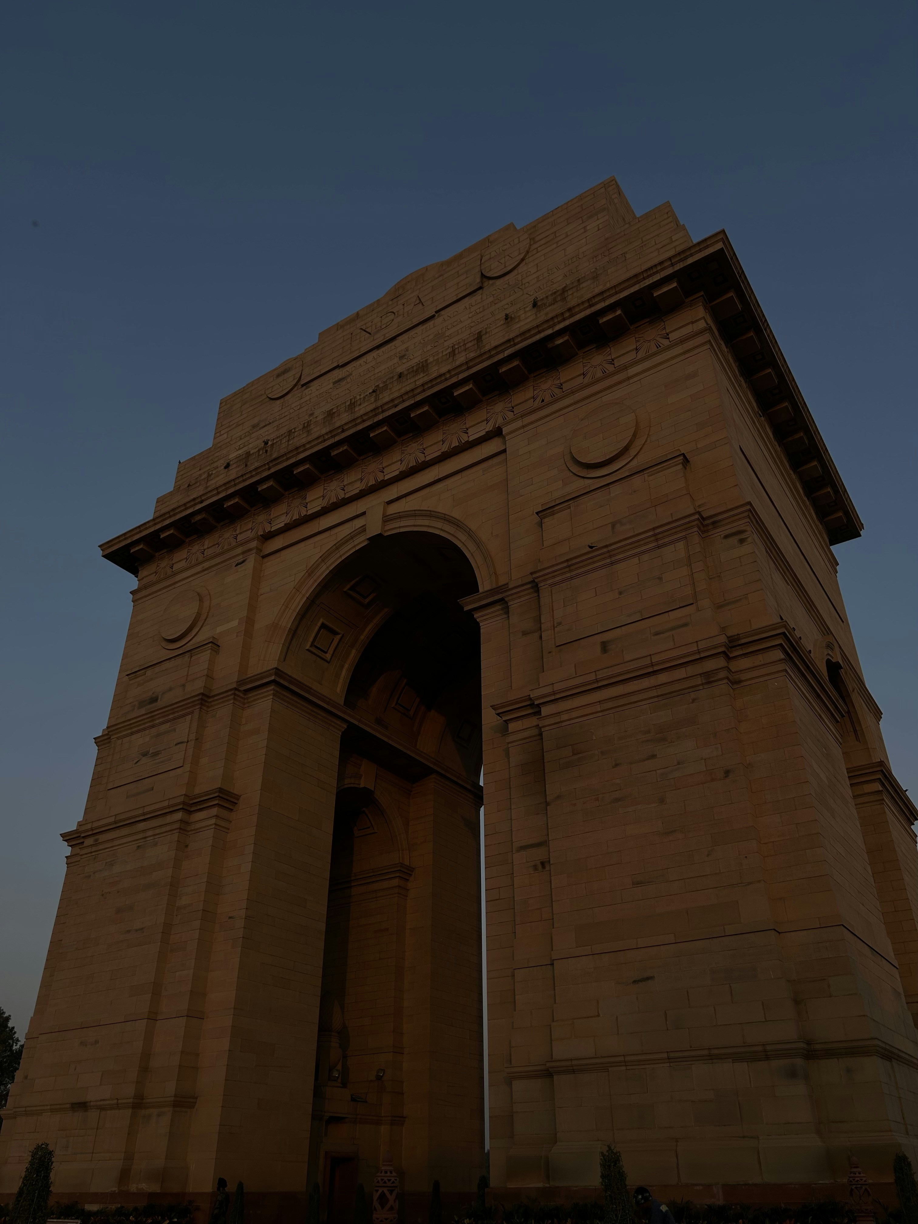India Gate monument in New Delhi at dusk with warm amber and blue twilight sky, clean empty plaza