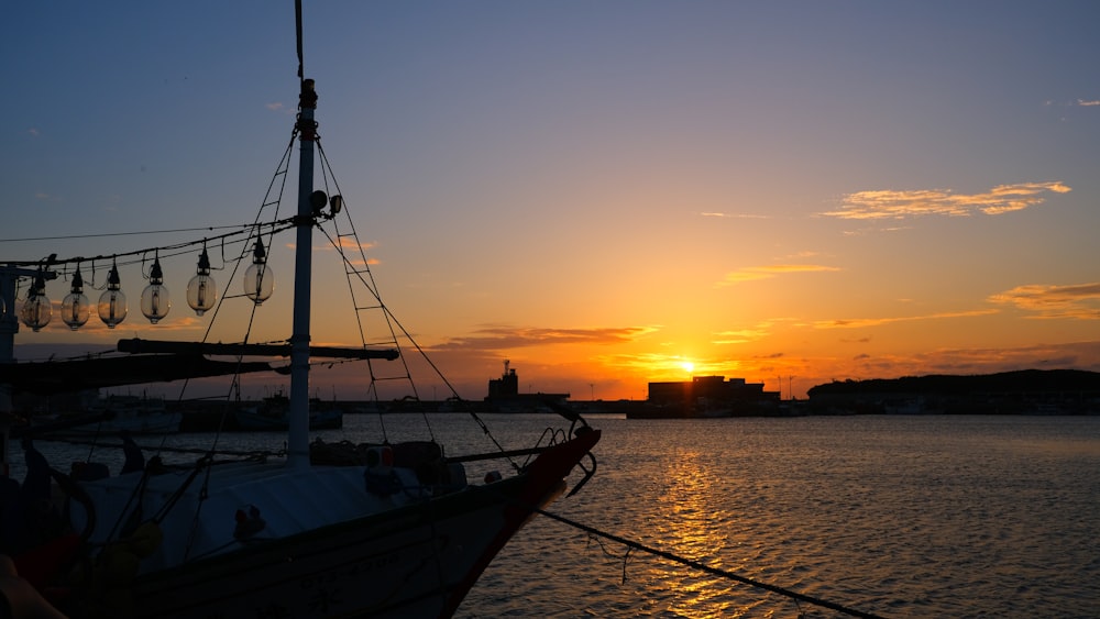 the sun is setting behind a boat in the water