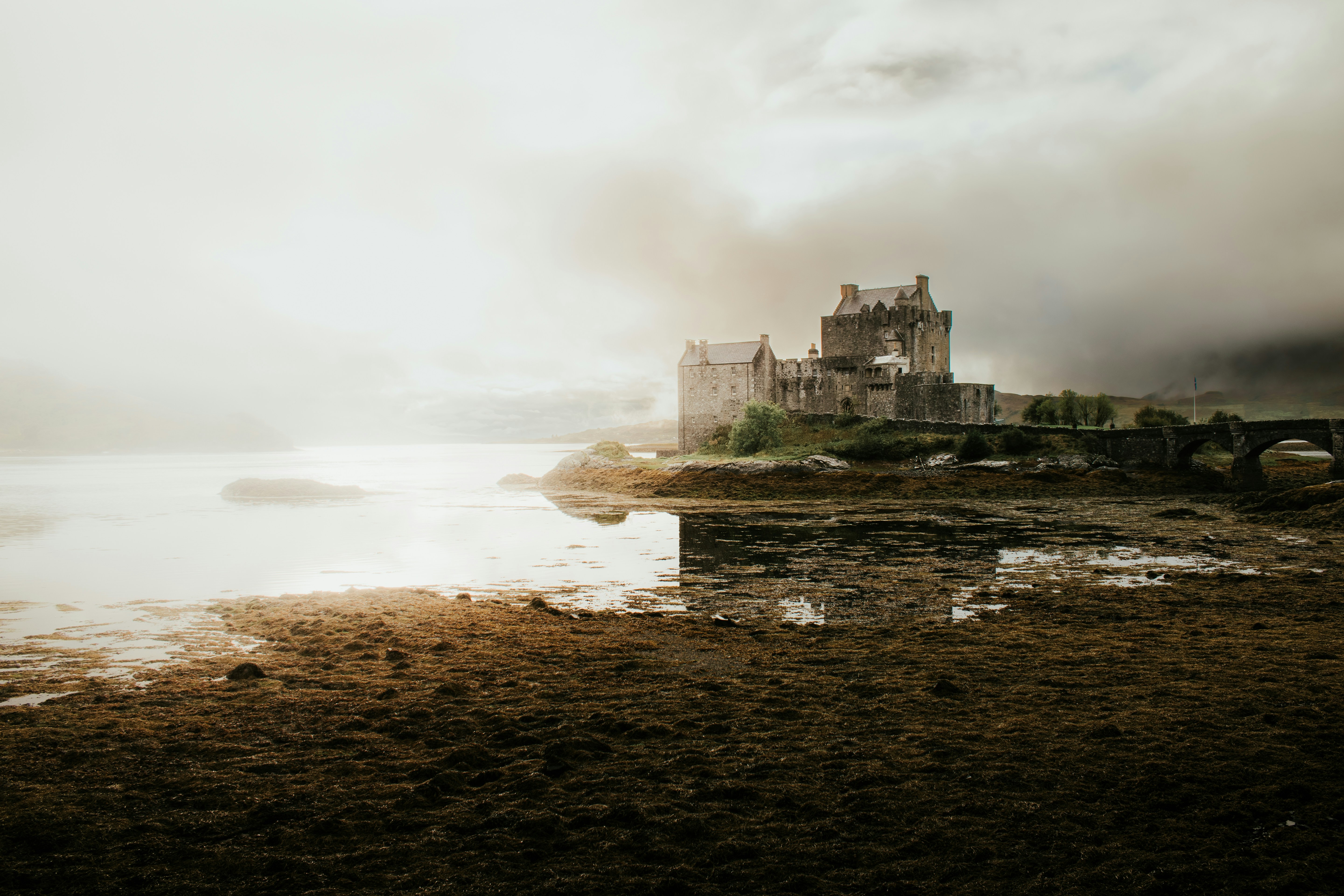 A dramatic medieval castle perched on a cliff above calm water, evoking the gothic towers and battlements of Hogwarts
