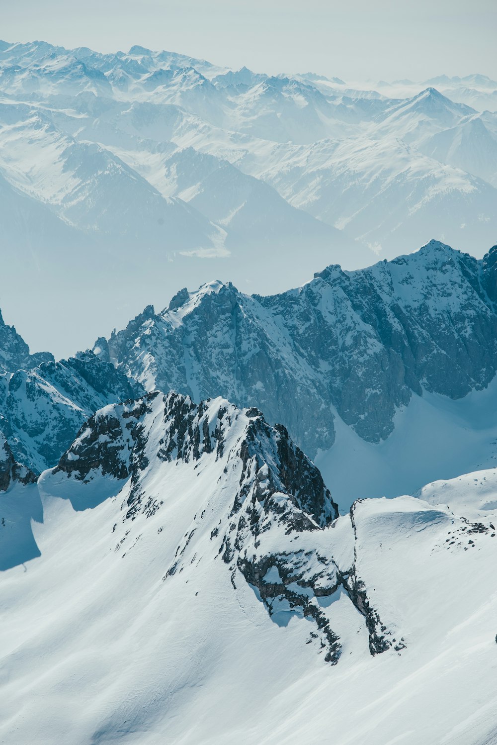 a mountain range covered in snow with mountains in the background