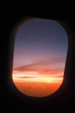 A vibrant sunset view from an airplane window over a mountain range.