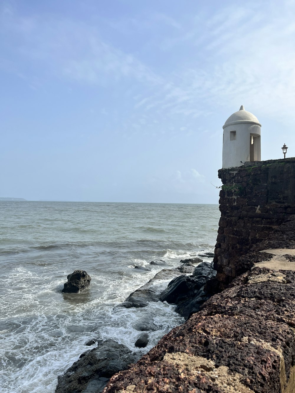 a lighthouse on the edge of a cliff near the ocean