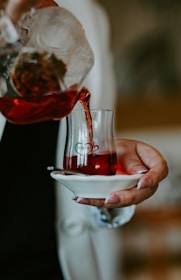 A close-up of hands demonstrating tea pouring in a workshop setting.
