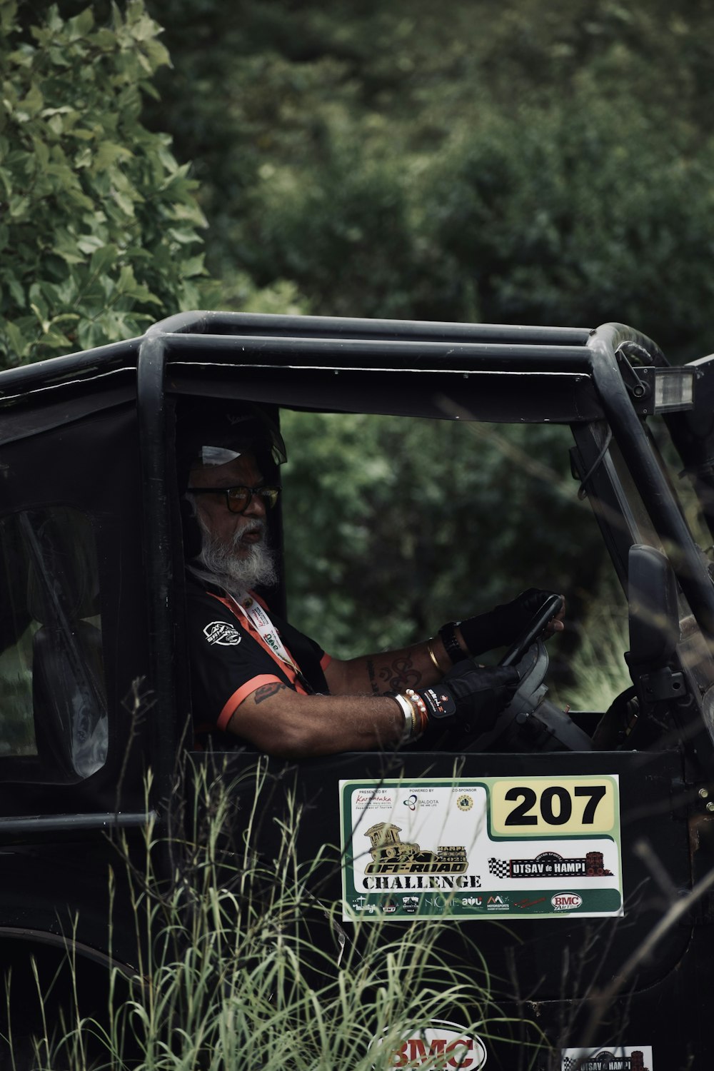 a man driving a jeep through a lush green forest