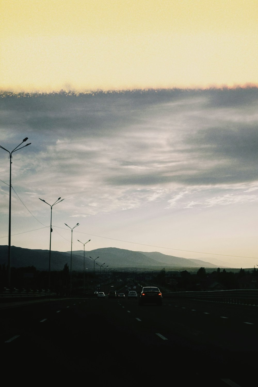 a car driving down a highway under a cloudy sky