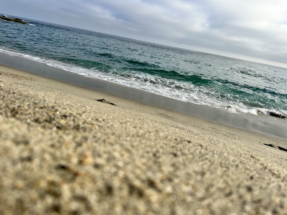 a sandy beach next to the ocean under a cloudy sky