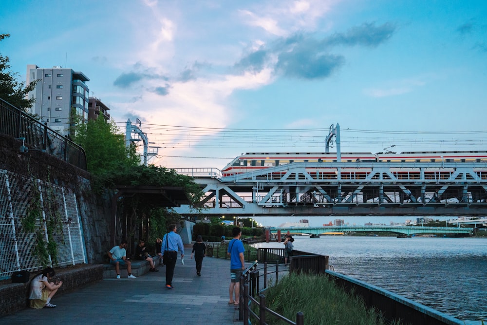 people walking on a sidewalk near a river