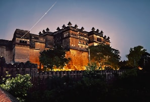 A nighttime shot of the fort hotel illuminated against a deep blue sky, highlighting its historic architecture.