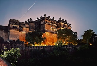 A nighttime shot of the fort hotel illuminated against a deep blue sky, highlighting its historic architecture.
