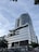 A modern, multi-story building with a sleek, metallic design. The facade features a large cylindrical structure with signage for a theme park. Glass windows and geometric patterns adorn the exterior, while palm trees add a touch of greenery at ground level.