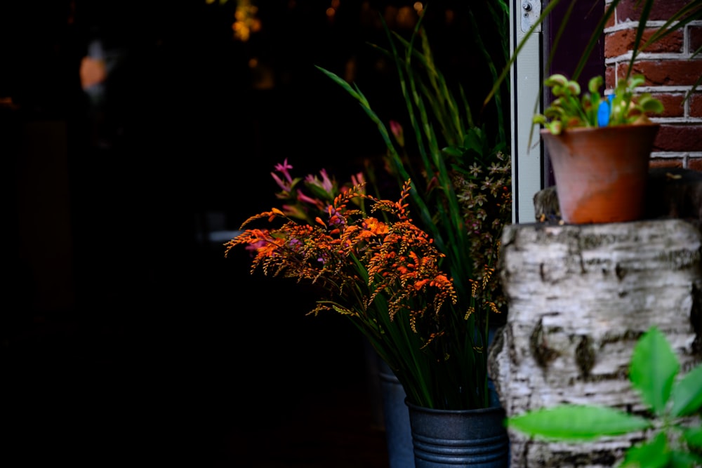 a couple of vases filled with flowers next to a brick wall