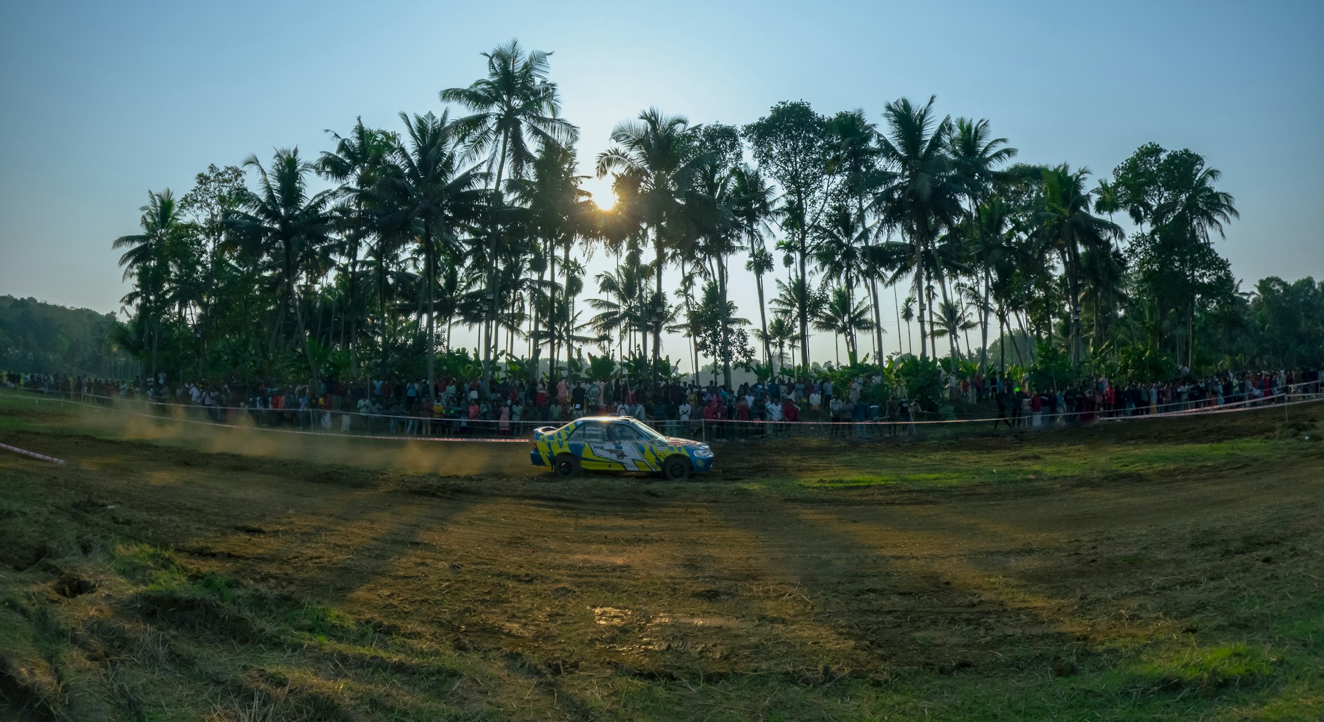 A thrilling moment on the kart track as a racer zooms past, surrounded by cheering spectators and the natural forest backdrop.
