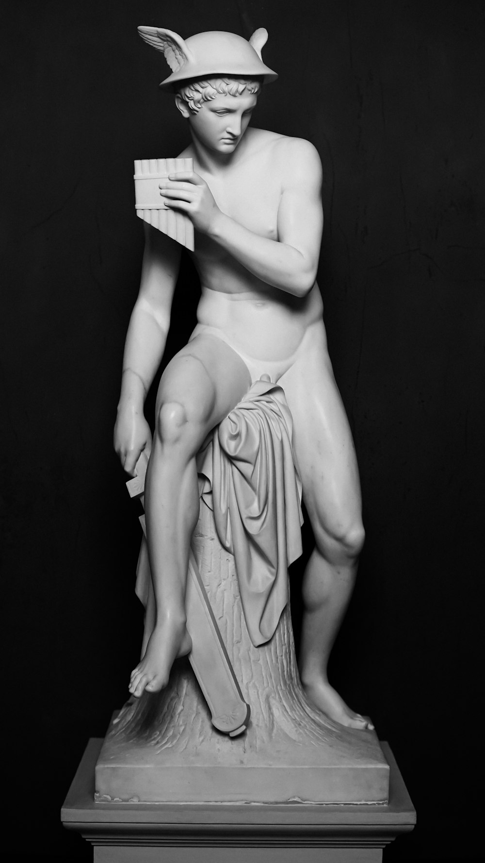 a black and white photo of a statue of a man reading a book