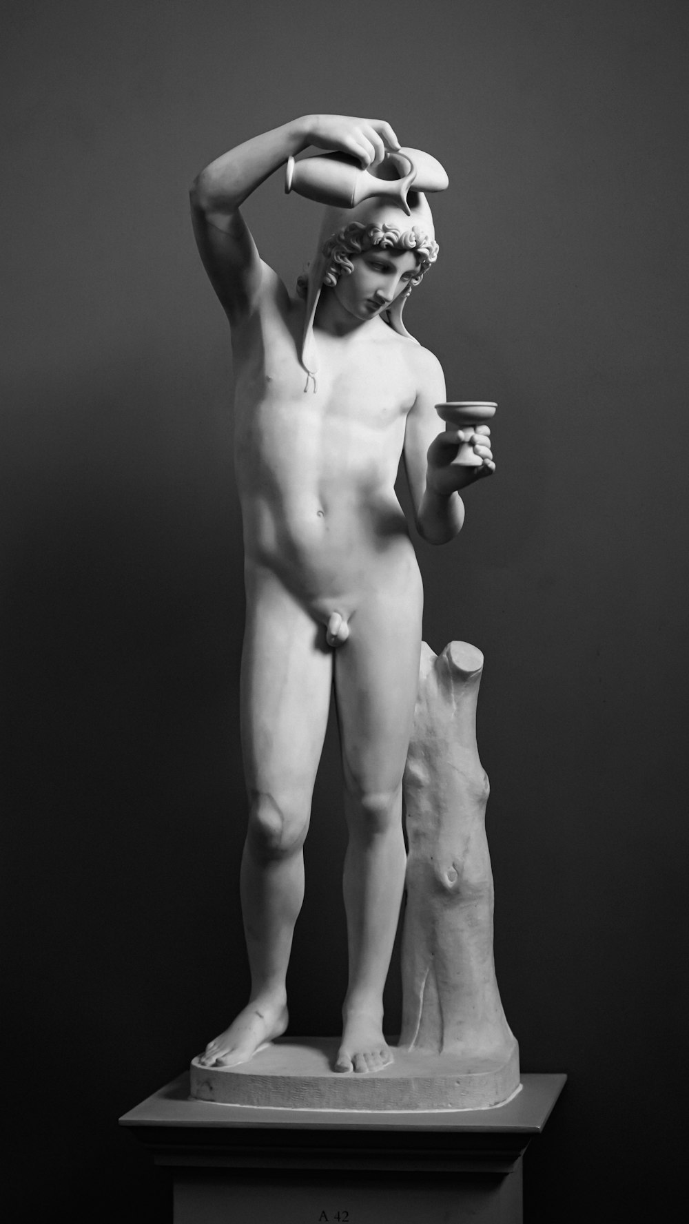a black and white photo of a statue of a man holding a cup