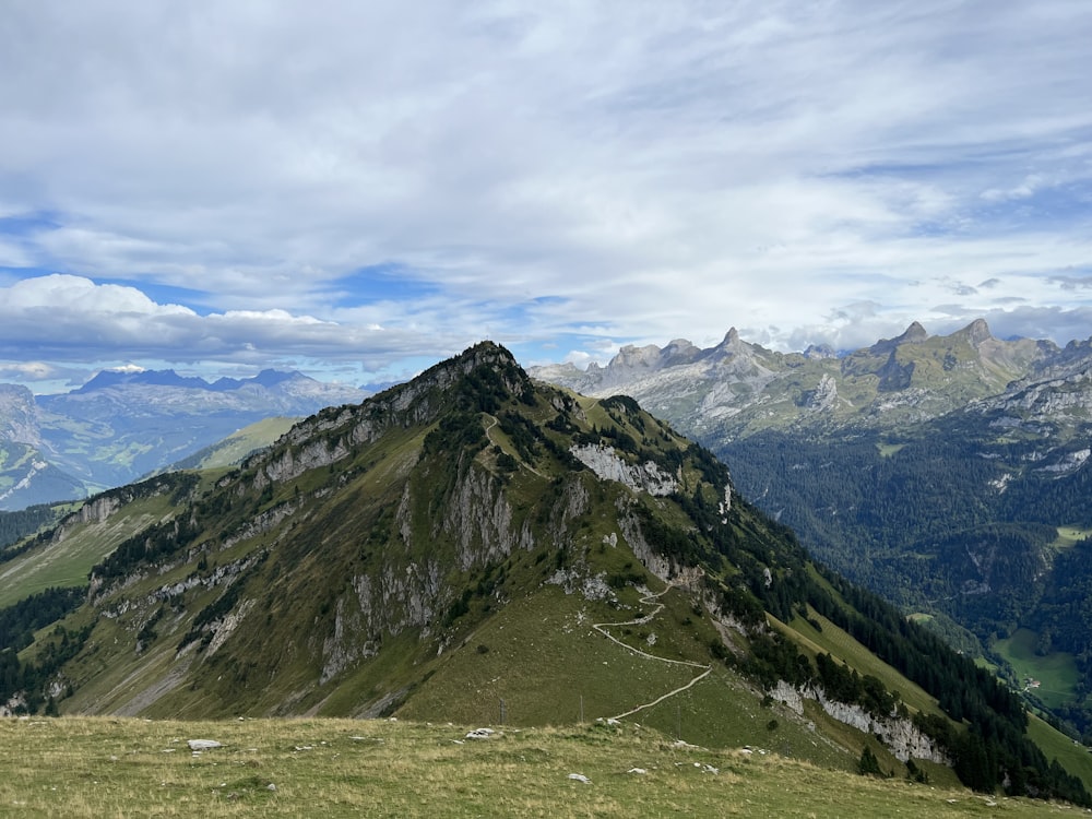 a view of a mountain with a grassy field below