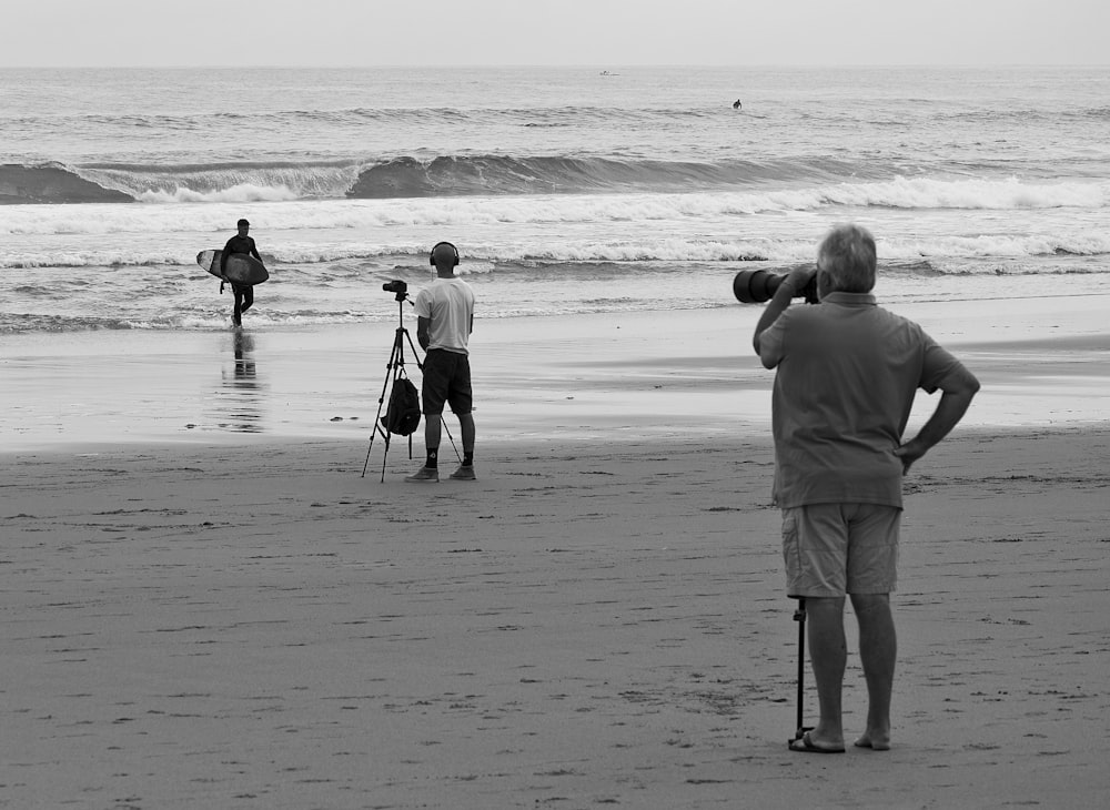 a group of people standing on top of a beach next to the ocean