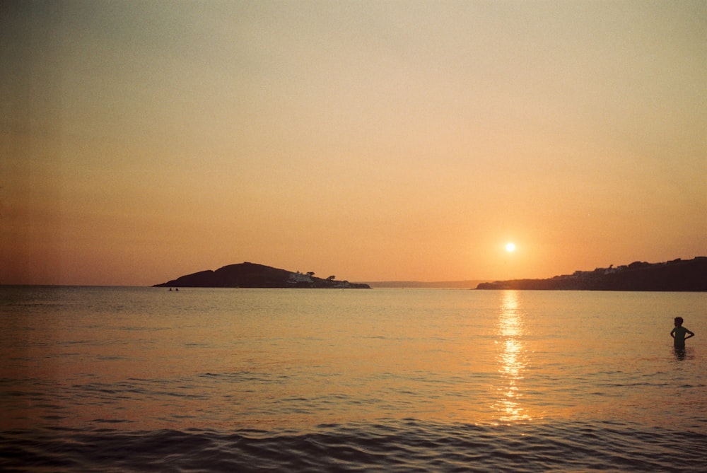 a person standing in the water at sunset