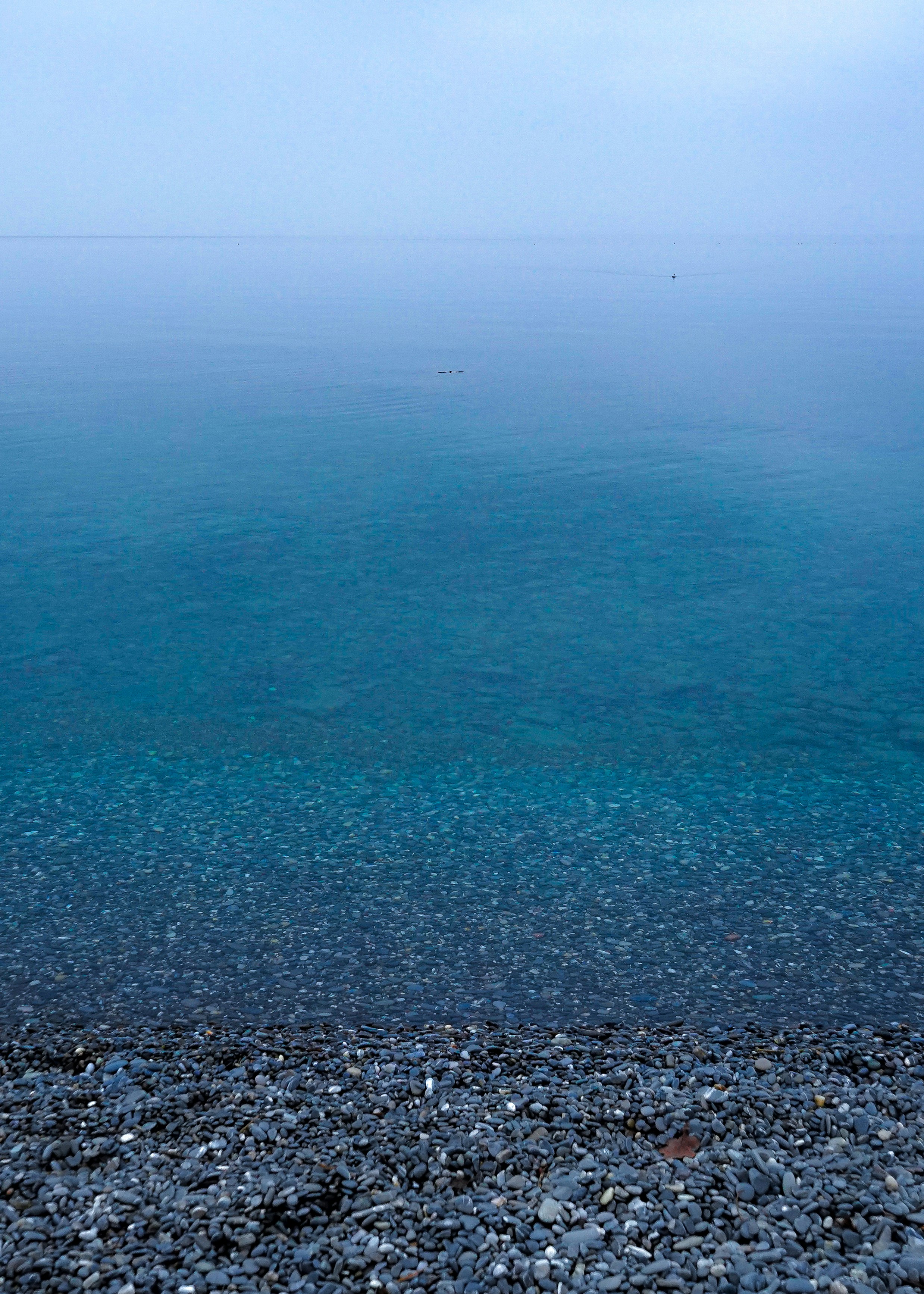 a bench sitting on top of a rocky beach next to the ocean