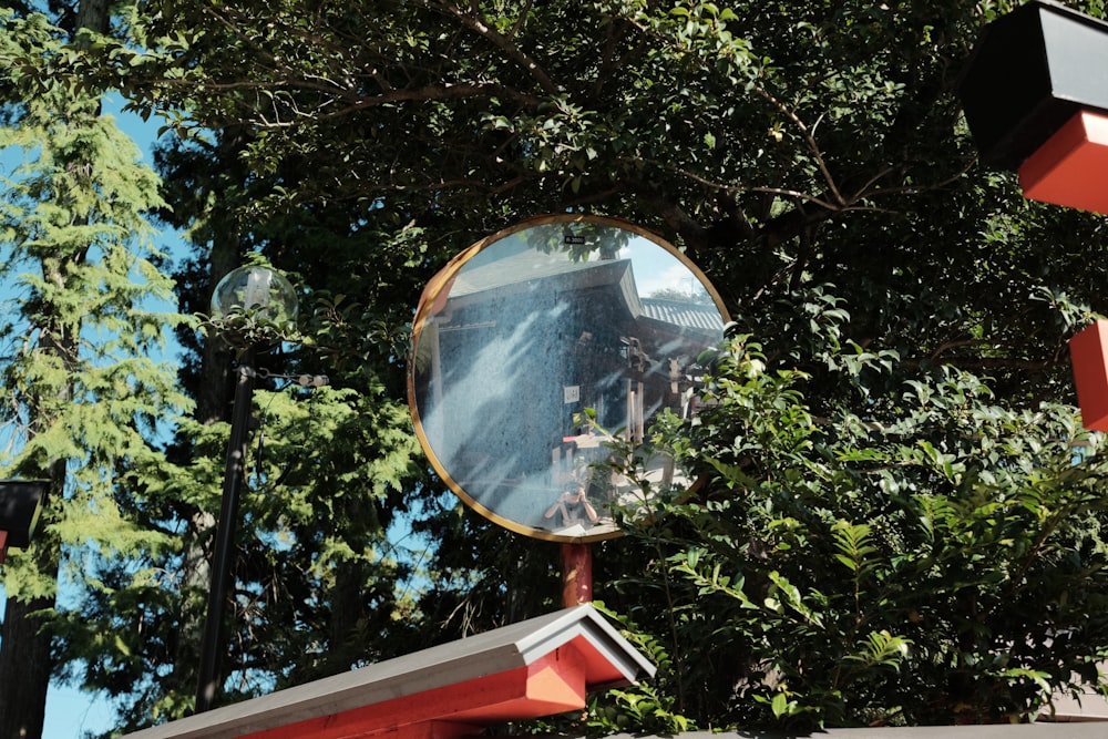 a mirror on a pole in front of a tree
