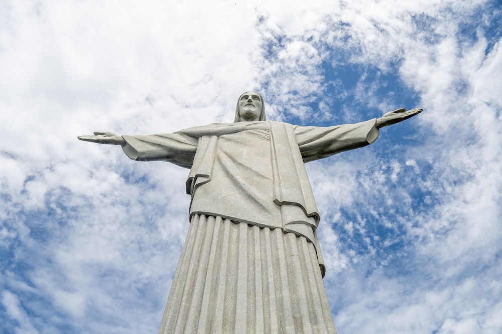 the statue of christ is in front of a cloudy blue sky