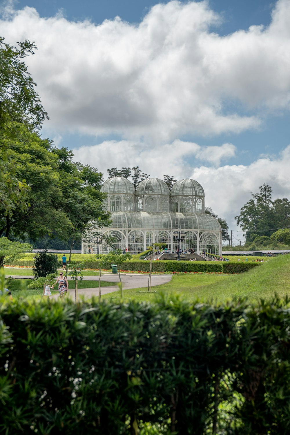 a large glass house sitting in the middle of a lush green park