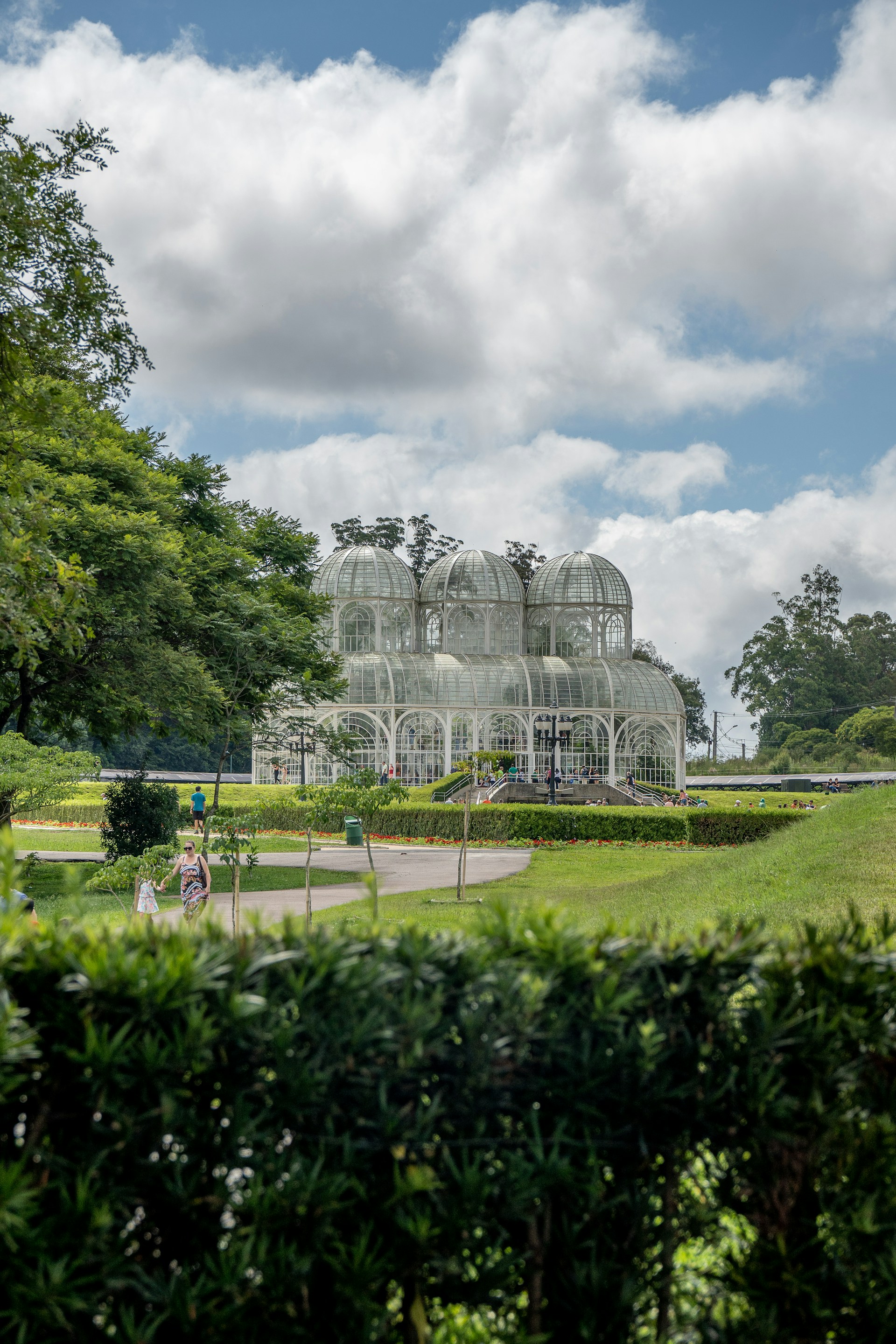 a large glass house sitting in the middle of a lush green park