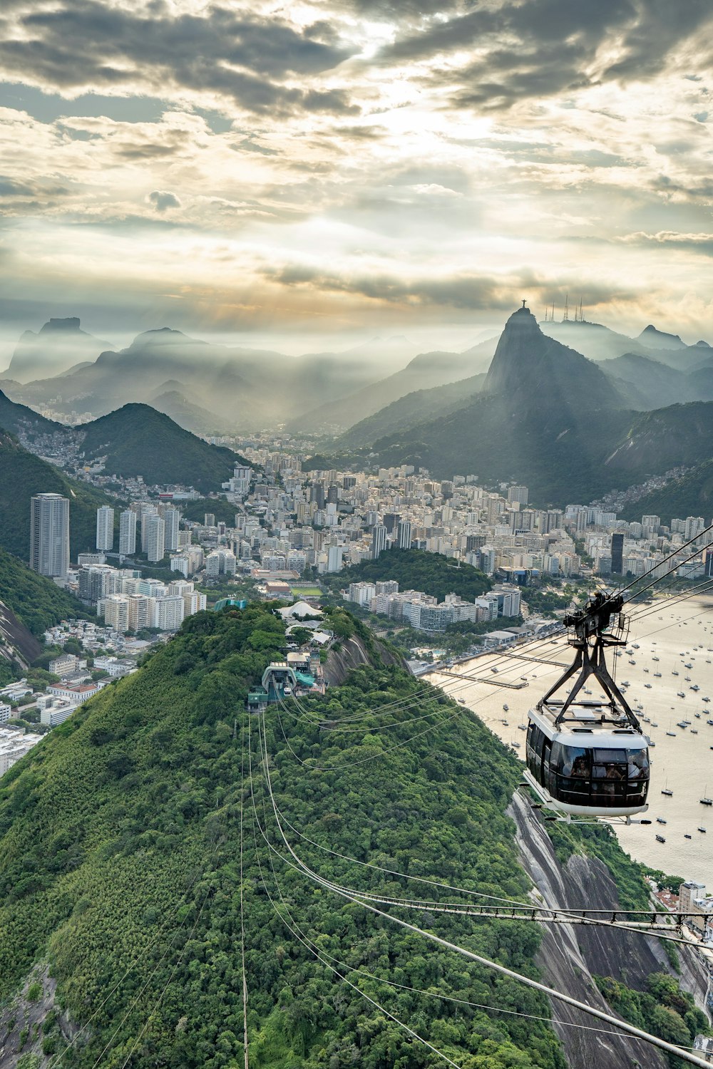 a cable car going up a mountain with a city in the background